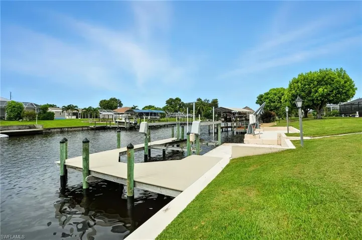 Dock area featuring a lawn, boat lift, and a water view