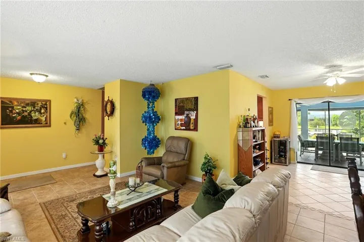 Living room featuring a textured ceiling, light tile patterned flooring, ceiling fan, and wine cooler