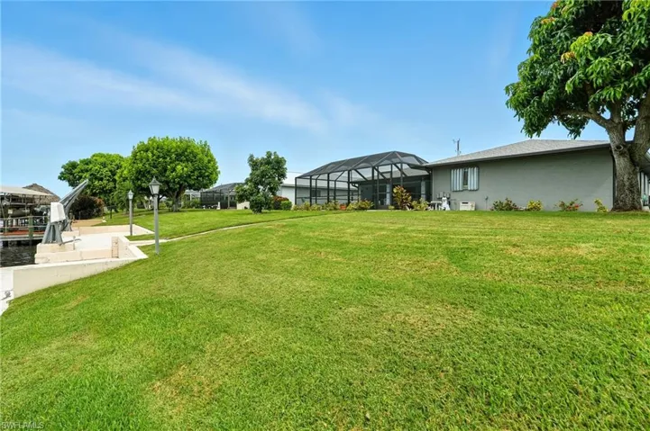 View of grassy yard featuring a sunroom and glass enclosure