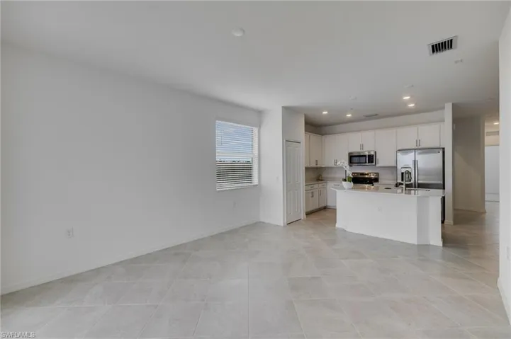 Kitchen featuring an island with sink, stainless steel appliances, white cabinets, recessed lighting, and open floor plan