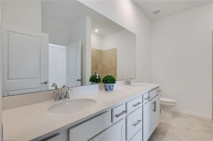 Full bath featuring double vanity and light tile patterned floors