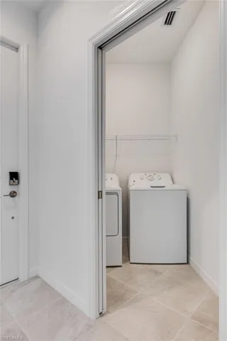 Laundry room featuring washing machine and dryer and light tile patterned floors