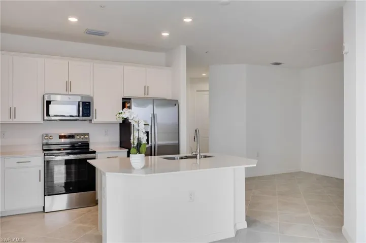 Kitchen with stainless steel appliances, white cabinets, a kitchen island with sink, light tile patterned floors, and recessed lighting