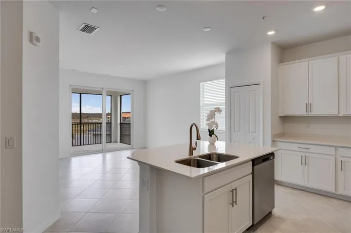 Kitchen with white cabinetry, dishwasher, light tile patterned flooring, a center island with sink, and recessed lighting