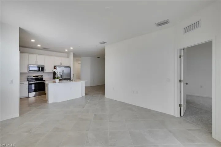 Kitchen with stainless steel appliances, open floor plan, white cabinetry, a center island with sink, and recessed lighting