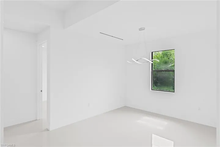 Empty room featuring baseboards and a chandelier