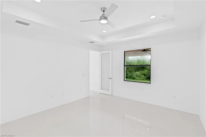Spare room with a tray ceiling, recessed lighting, and ceiling fan