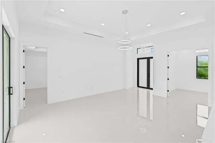 Unfurnished room featuring a tray ceiling, recessed lighting, and french doors
