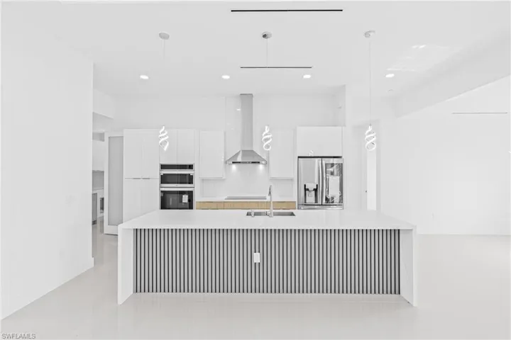 Kitchen featuring white cabinetry, modern cabinets, a spacious island, and stainless steel fridge with ice dispenser