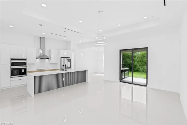 Kitchen featuring a center island with sink, decorative light fixtures, white cabinets, modern cabinets, and stainless steel appliances