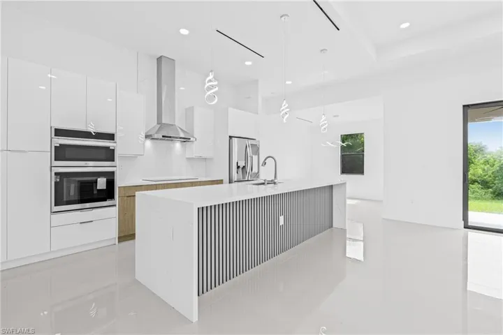 Kitchen featuring pendant lighting, white cabinetry, modern cabinets, stainless steel appliances, and light stone countertops