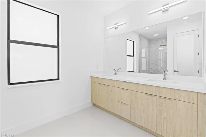 Full bathroom featuring double vanity and a marble finish shower