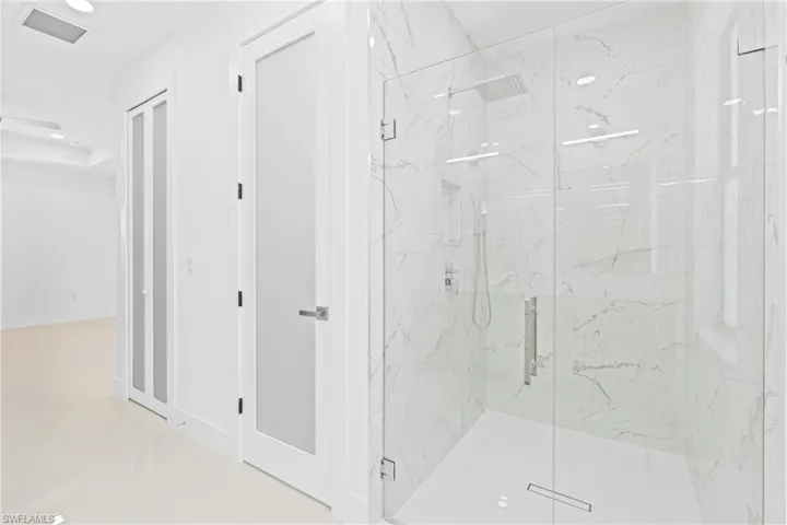 Bathroom with a marble finish shower and recessed lighting