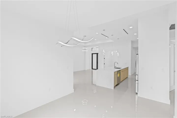 Kitchen with pendant lighting, light stone countertops, a center island with sink, stainless steel appliances, and modern cabinets