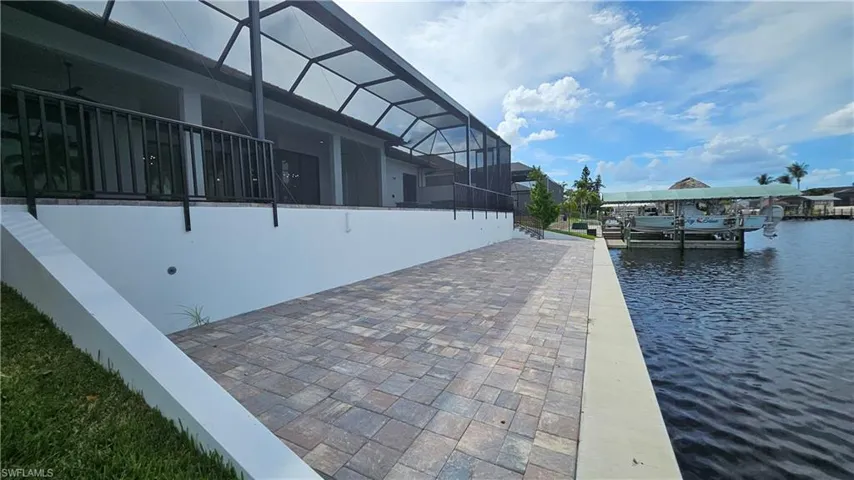 View of home's exterior featuring a lanai, a boat dock, a water view, a sunroom, and boat lift