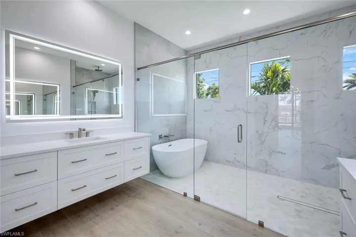 Enjoy this luxurious master suite, featuring a spa-like ensuite with floating cabinets, LED-backlit mirrors, a porcelain tile shower, and a standalone soaking tub.