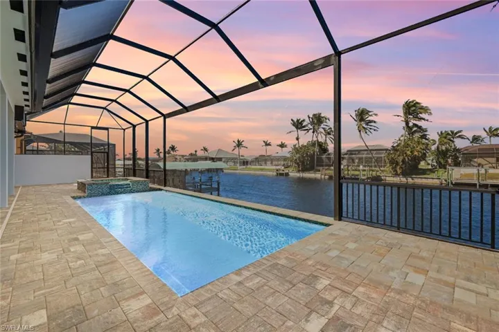 View of pool with a water view, a boat dock, a pool with connected hot tub, a patio, and a lanai