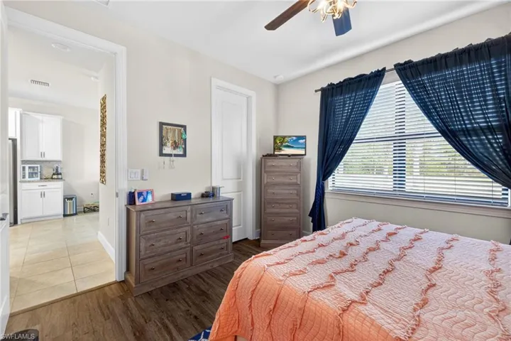 Bedroom featuring wood-finish flooring, a ceiling fan with integrated lighting, and a large window with blinds