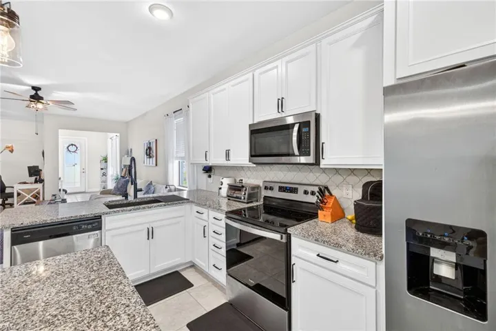 Modern kitchen featuring white cabinetry, granite countertops, and stainless steel appliances