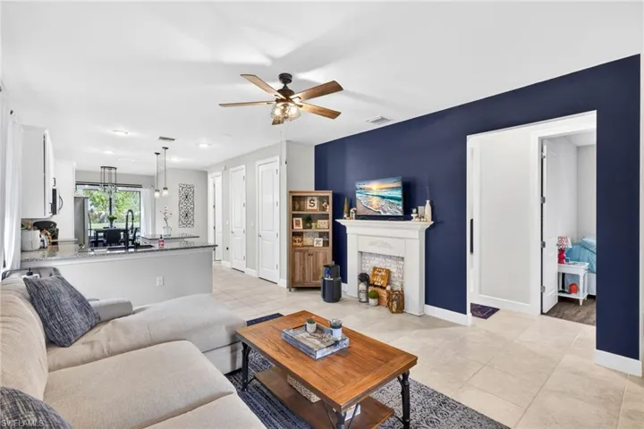 Open-concept living area featuring tile flooring and a decorative fireplace with white mantel and brick-look surround