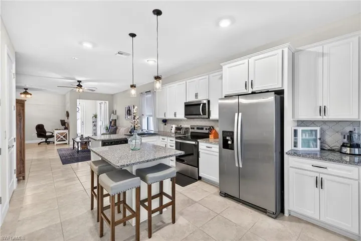 Modern kitchen featuring white shaker cabinetry with dark hardware, granite countertops, and stainless steel appliances