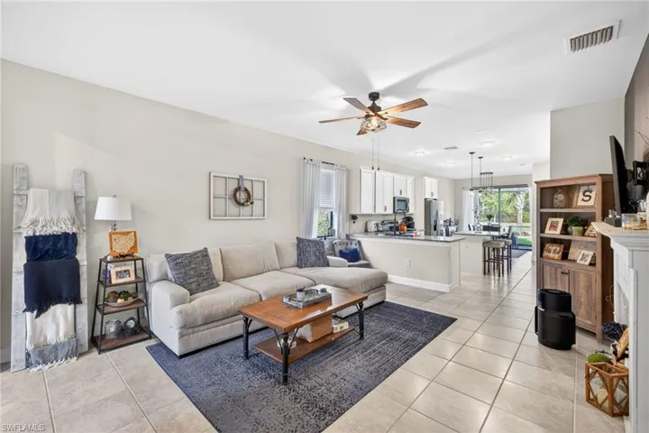 Spacious open-concept living area featuring light-toned tile flooring, recessed lighting, and a ceiling fan