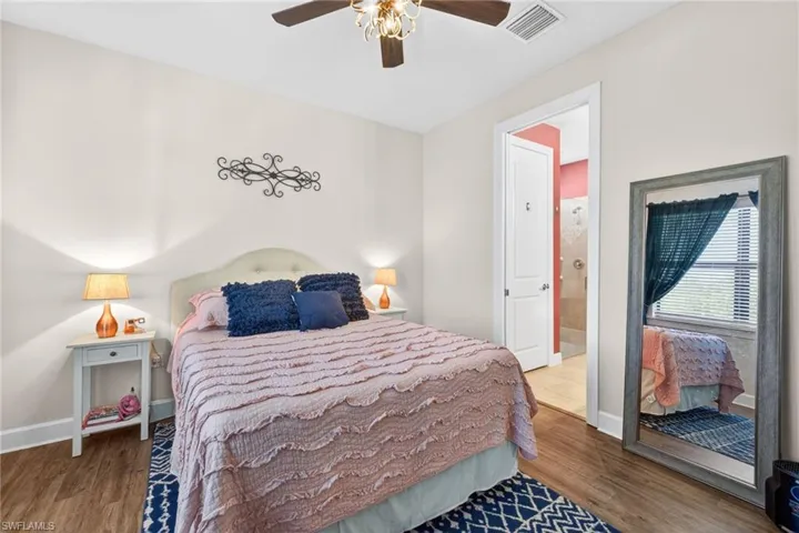 Bedroom featuring wood-finish flooring, a ceiling fan with integrated lighting, and direct access to a bathroom with a tiled shower