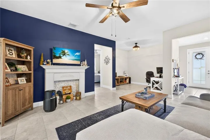 Living area featuring a decorative fireplace with white surround and brick-patterned tile, complemented by a prominent blue accent wall