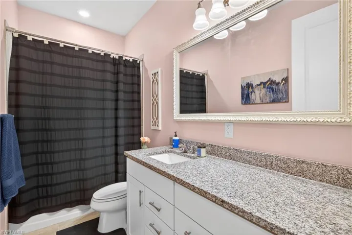 Bathroom featuring a white vanity with brushed nickel hardware, granite countertop, and integrated sink