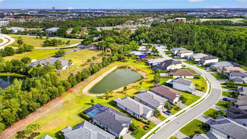 Aerial perspective showcasing a residential community with winding streets, surrounding green spaces, and a prominent pond