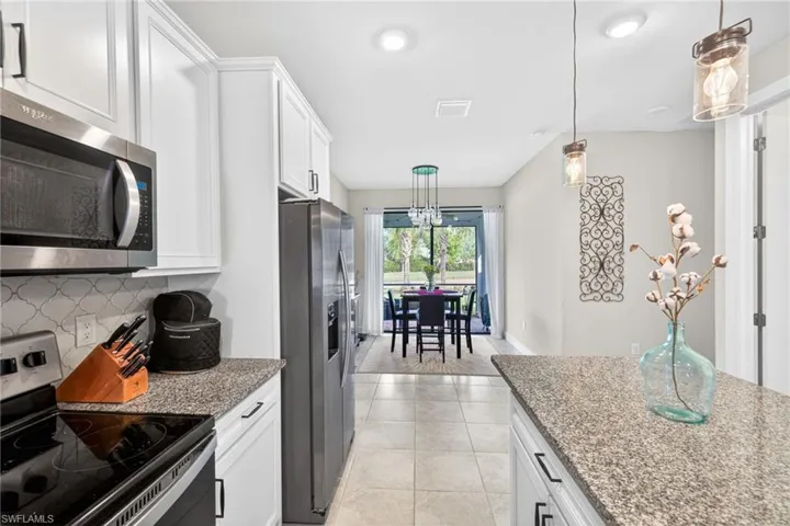 Modern kitchen featuring white cabinetry, granite-finish countertops, stainless steel appliances, and a tiled backsplash