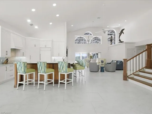 Kitchen featuring paneled fridge, a kitchen bar, high vaulted ceiling, open floor plan, and custom exhaust hood