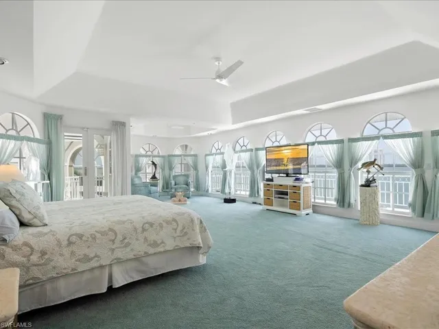 Carpeted bedroom featuring french doors, a raised ceiling, a ceiling fan, and access to outside