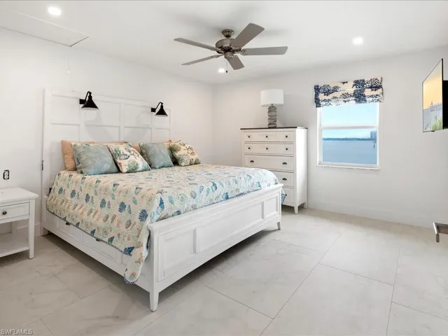 Bedroom featuring baseboards, marble finish floor, attic access, and ceiling fan