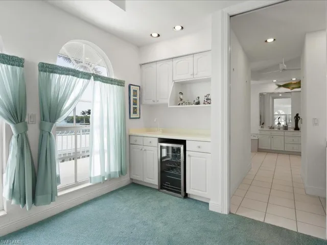 Bar with wine cooler, light tile patterned floors, light carpet, recessed lighting, and indoor wet bar