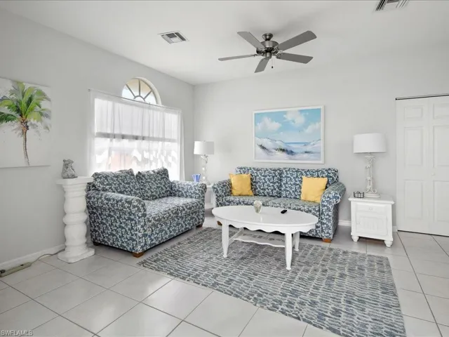 Living area featuring light tile patterned flooring, visible vents, baseboards, and a ceiling fan