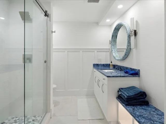 Full bathroom featuring a stall shower, wainscoting, and a decorative wall