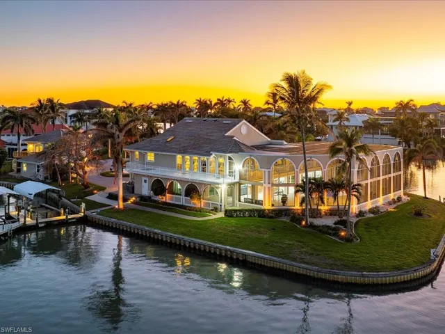 Rear view of house featuring stucco siding, a water view, a yard, glass enclosure, and a balcony