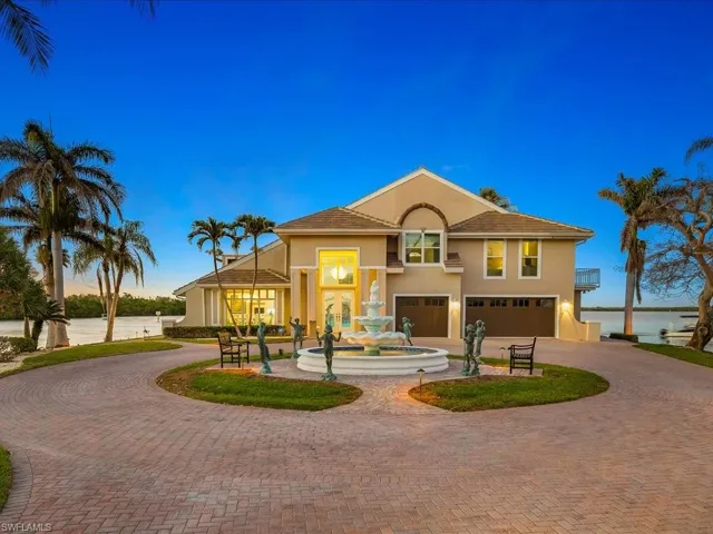 View of front of house featuring stucco siding, a water view, curved driveway, and a garage