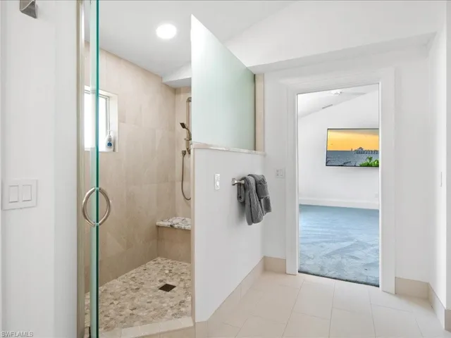 Bathroom with tile patterned floors, baseboards, walk in shower, and vaulted ceiling
