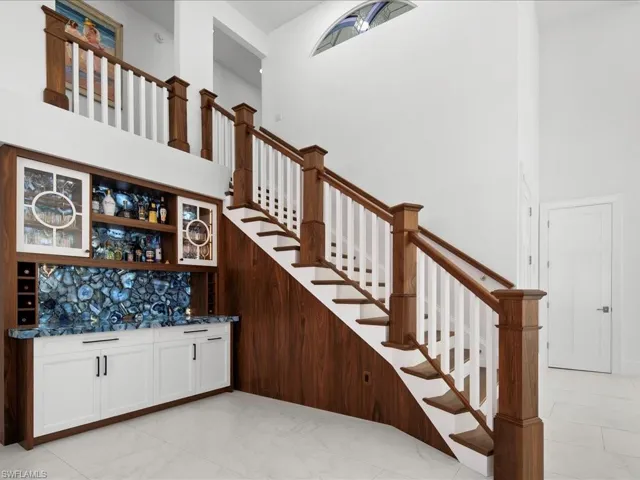 Staircase with wet bar, a high ceiling, and marble finish floor