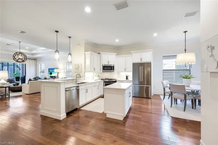 Kitchen with dark wood-type flooring, sink, kitchen peninsula, pendant l