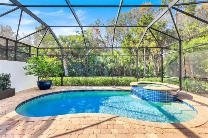 View of pool with an in ground hot tub, glass enclosure, and a patio