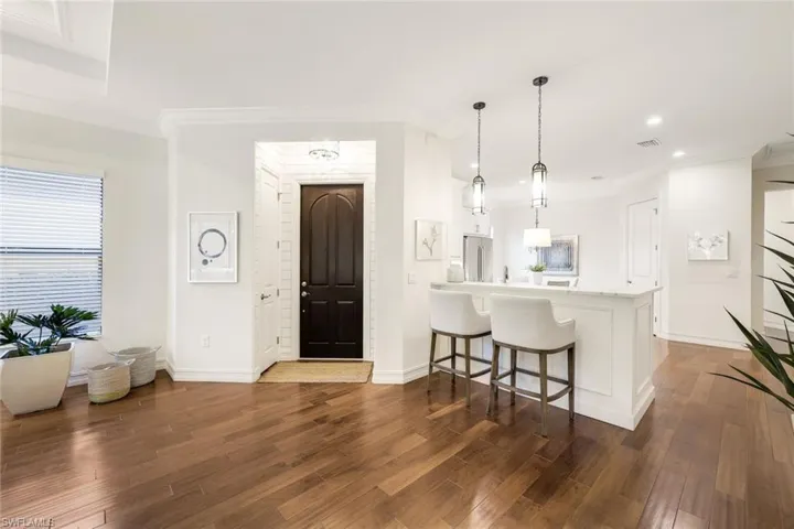 Kitchen with pendant lighting, stainless steel fridge, hardwood / wood-style floors, a kitchen bar, and kitchen peninsula
