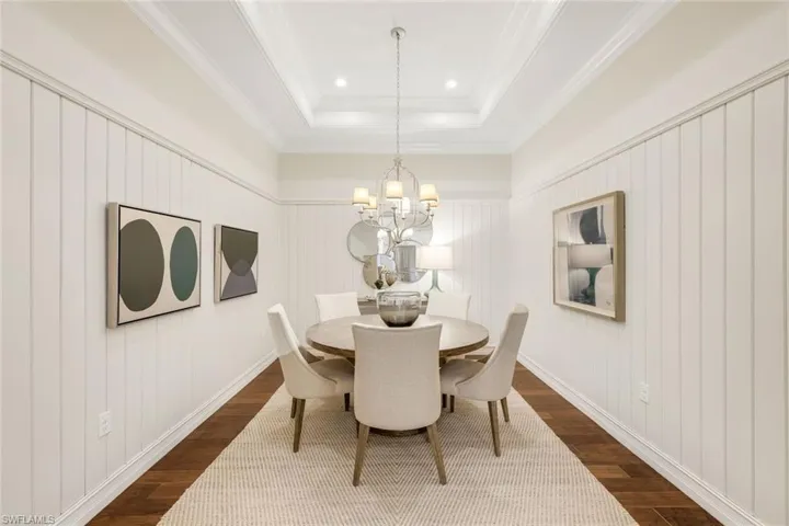 Dining space featuring wood-type flooring, ornamental molding, a notable chandelier, and a tray ceiling