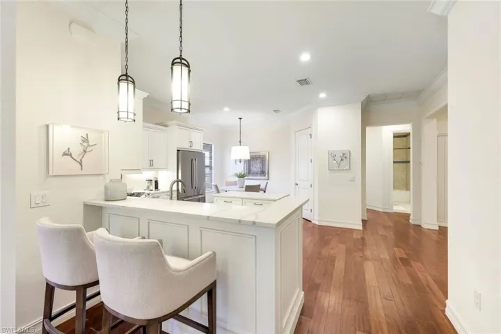 Kitchen featuring a kitchen bar, white cabinetry, hanging light fixtures, high quality fridge, and kitchen peninsula