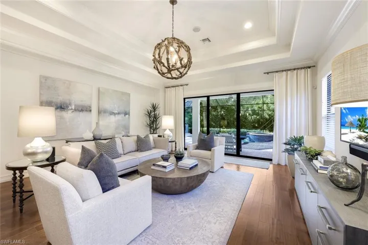 Living room featuring hardwood / wood-style flooring, ornamental molding, a raised ceiling, and a chandelier
