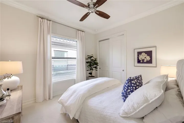 Carpeted bedroom featuring crown molding, ceiling fan, and a closet