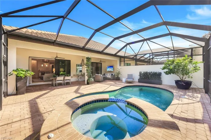 View of pool with an in ground hot tub, ceiling fan, a lanai, and a patio area