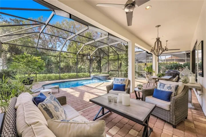 View of swimming pool featuring an in ground hot tub, a patio, an outdoor hangout area, and glass enclosure